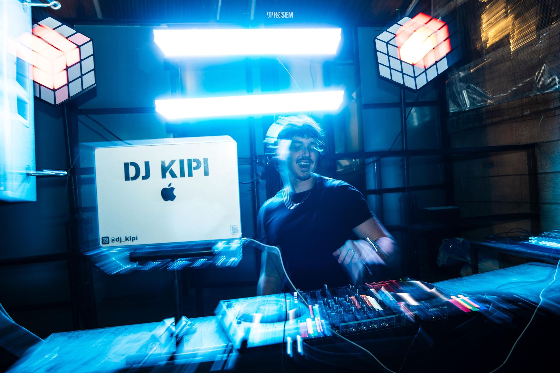 DJ KIPI מנגן מאחורי הדק בתאורת ניאון כחולה